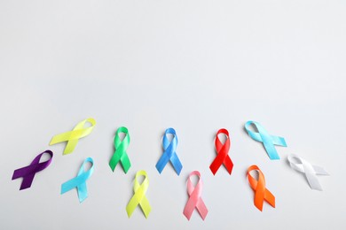 Photo of Different colorful ribbons on white background, flat lay with space for text. World Cancer Day