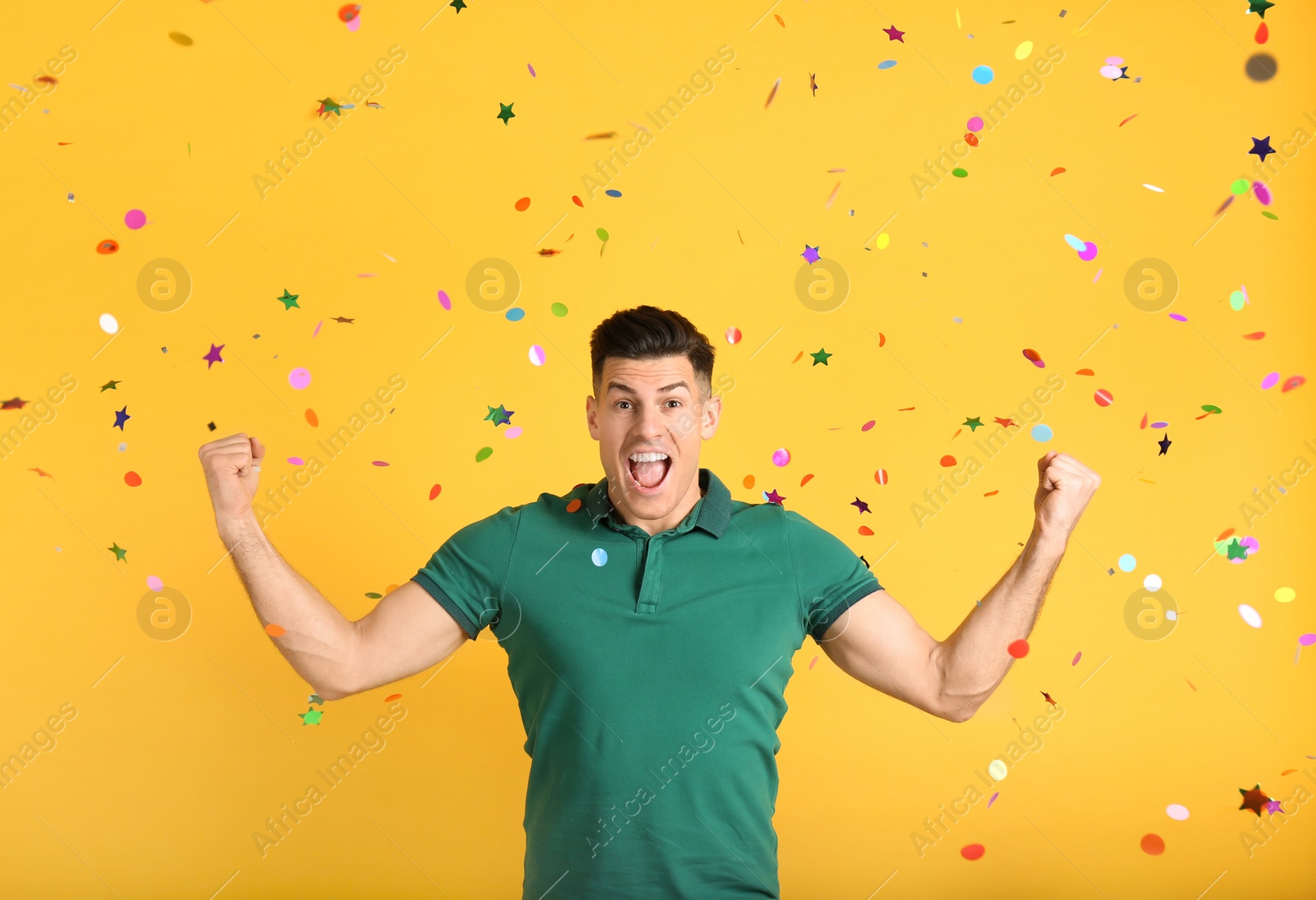 Photo of Emotional man and falling confetti on yellow background