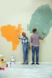 Photo of Young couple painting wall indoors. Home repair