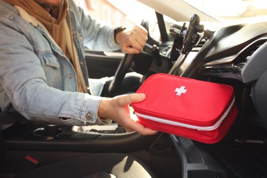 Photo of Man with first aid kit inside car, closeup