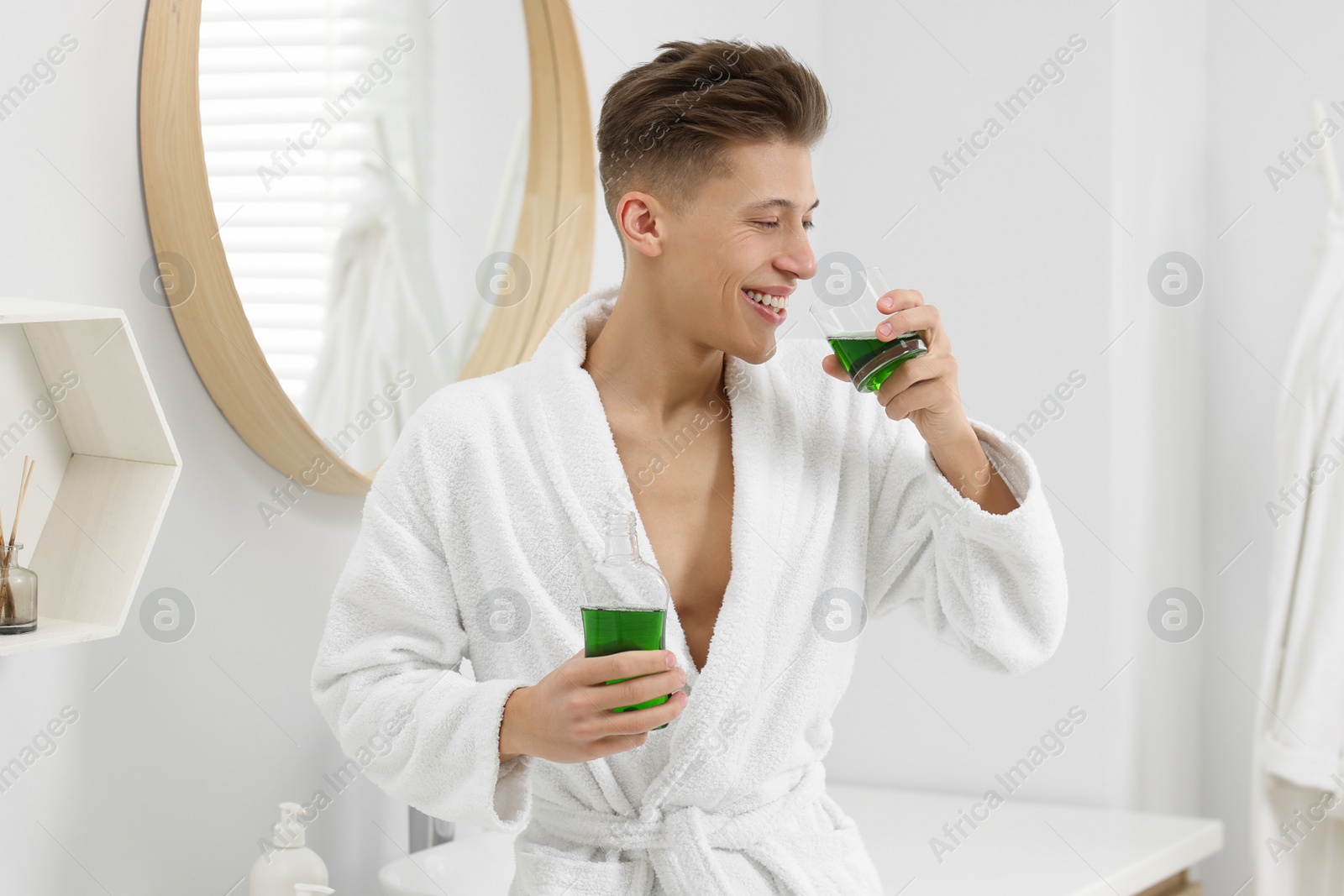 Photo of Young man using mouthwash in bathroom. Oral hygiene