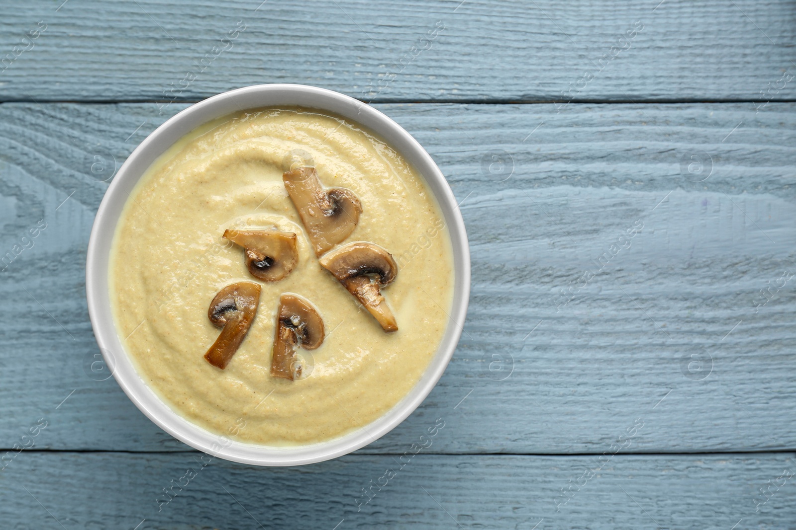 Photo of Delicious mushroom cream soup on light grey wooden table, top view. Space for text