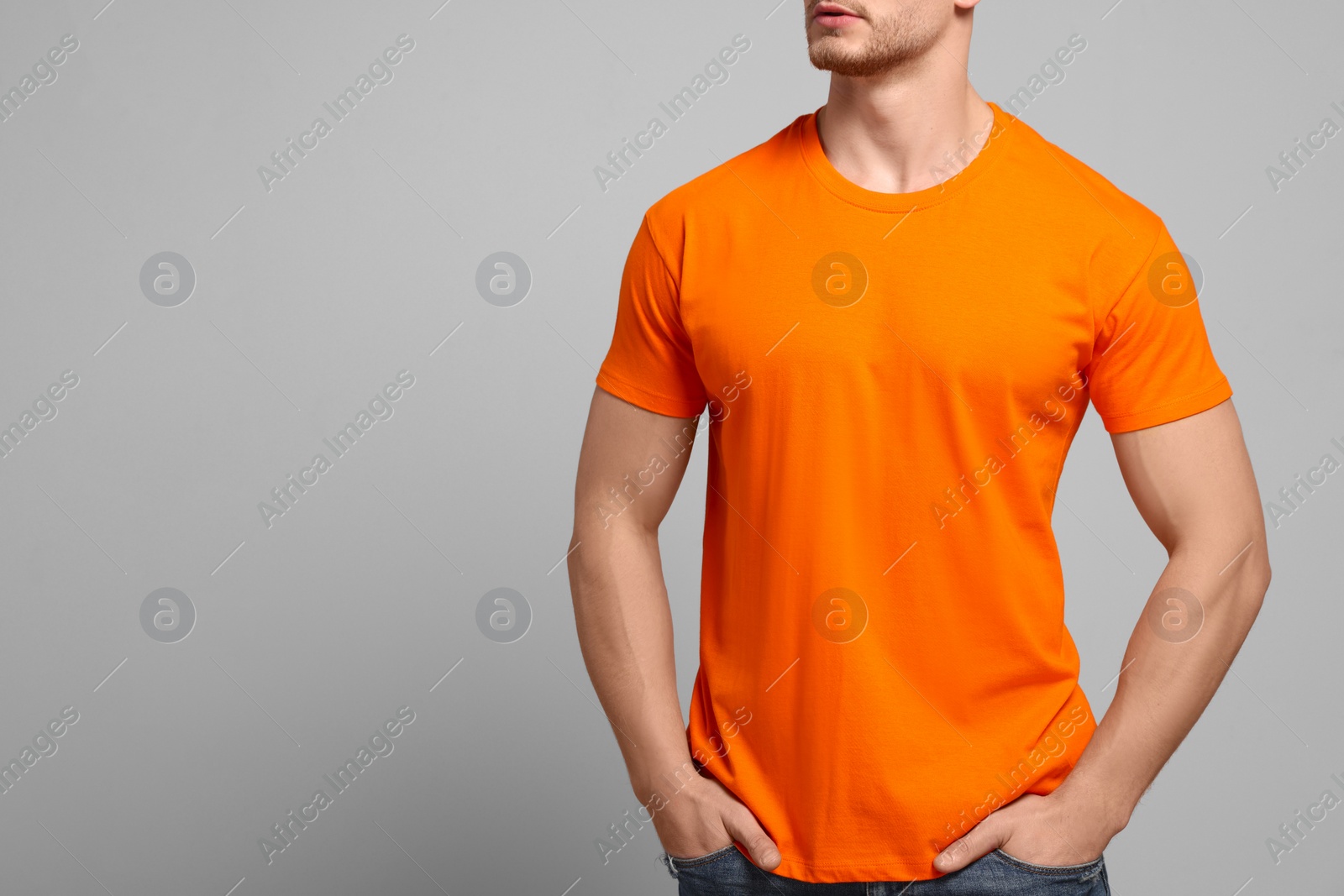 Photo of Man wearing orange t-shirt on light grey background, closeup. Mockup for design