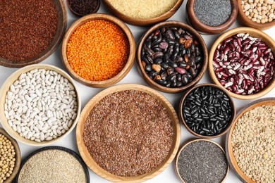 Photo of Various raw veggie seeds in bowls on white background, top view