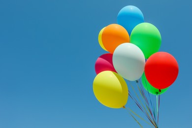 Photo of Bunch of colorful balloons against blue sky. Space for text