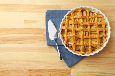 Photo of Tasty homemade quince pie and cake server on wooden table, top view. Space for text