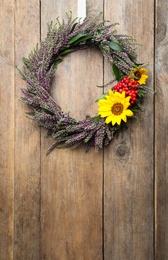Photo of Beautiful autumnal wreath with heather flowers hanging on wooden background. Space for text