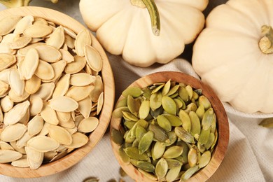 Bowls with seeds and fresh pumpkins on table, flat lay