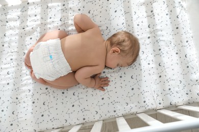 Photo of Cute little baby sleeping in crib, top view