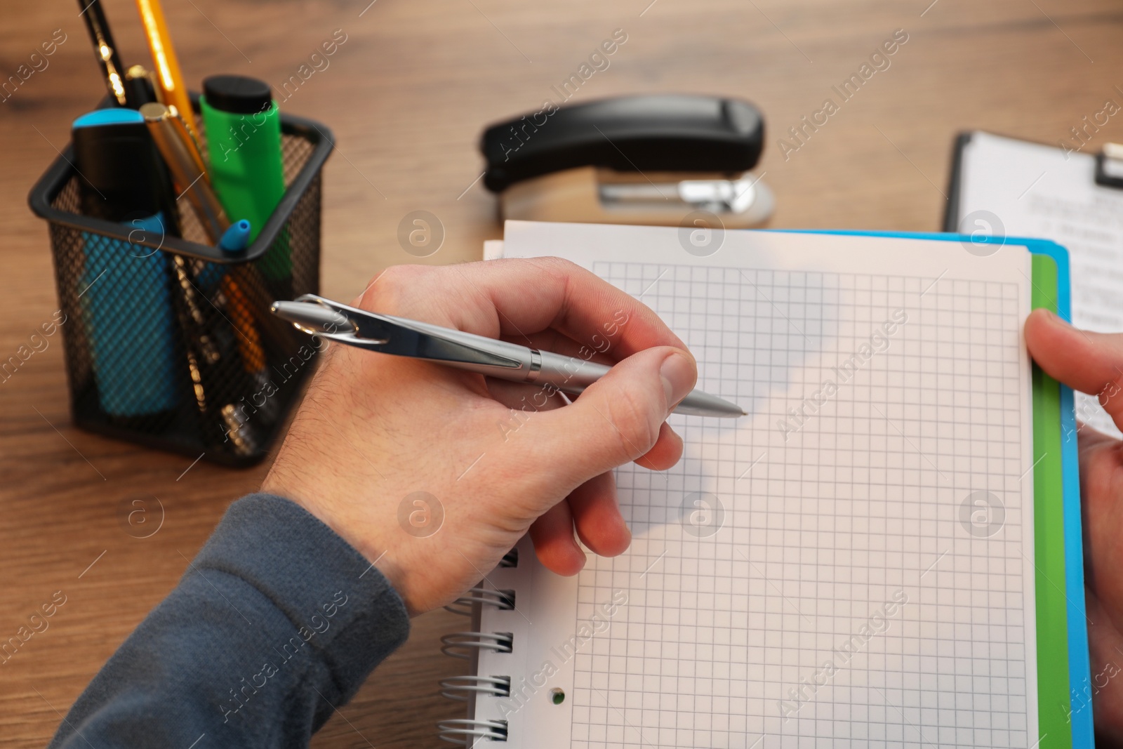 Photo of Man taking notes at wooden table, closeup