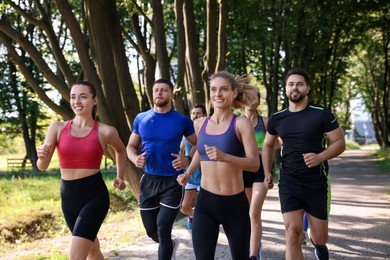 Photo of Group of people running in park on sunny day