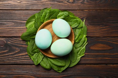 Photo of Naturally painted Easter eggs on wooden table, flat lay. Spinach used for coloring