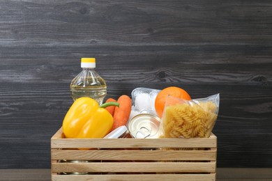 Photo of Crate with donation food against wooden background, closeup