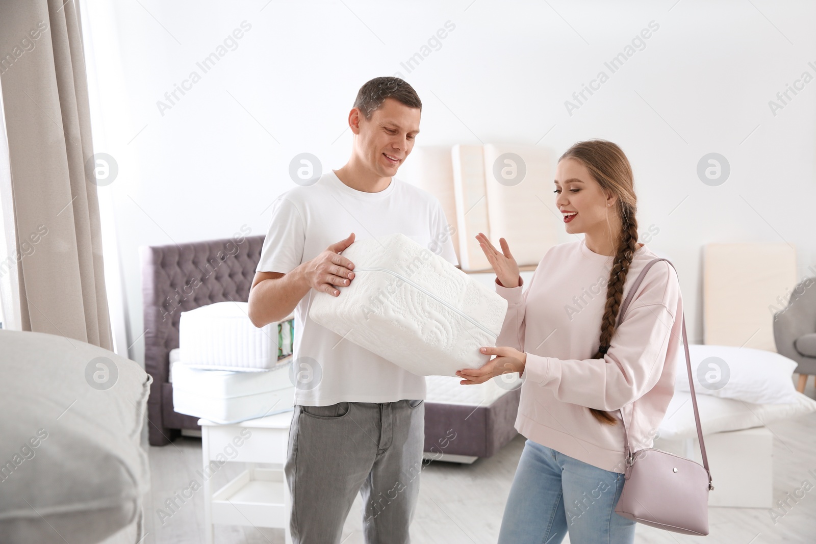 Photo of Happy couple choosing mattress in furniture store