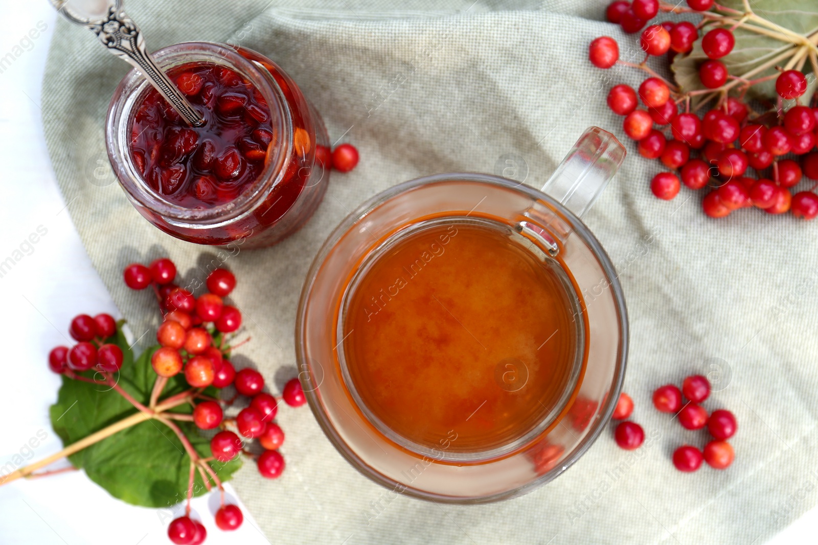 Photo of Cup of tea, jam and ripe viburnum berries on white table, flat lay