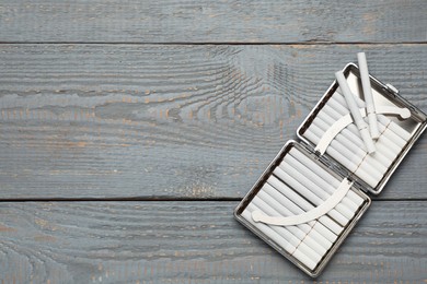 Stylish case with cigarettes on grey wooden table, top view. Space for text