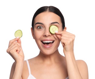 Photo of Beautiful young woman putting slices of cucumber on eyes against white background