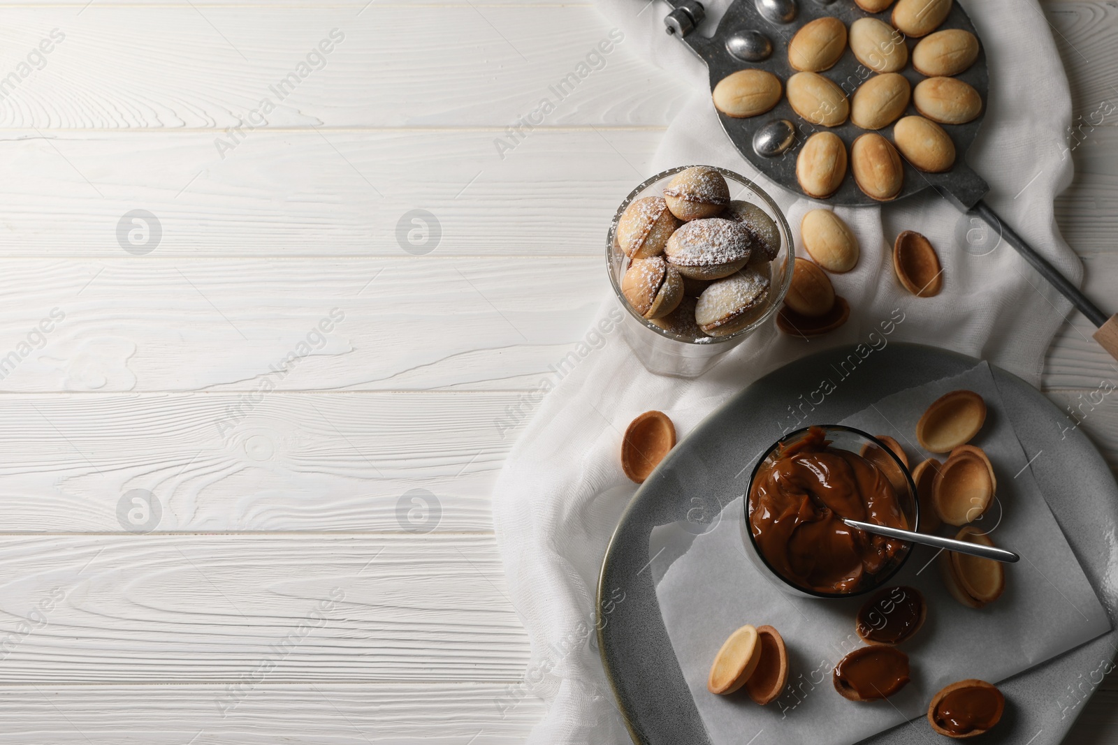 Photo of Delicious walnut shaped cookies with condensed milk on white wooden table, flat lay. Space for text
