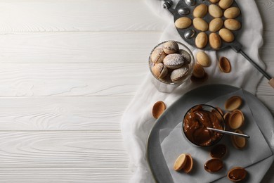 Delicious walnut shaped cookies with condensed milk on white wooden table, flat lay. Space for text