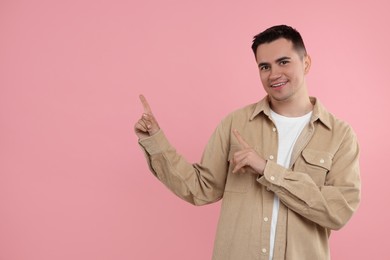 Special promotion. Happy man pointing at something on pink background, space for text