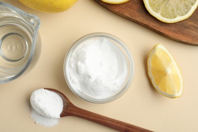Photo of Baking soda, lemons and vinegar on beige background, flat lay