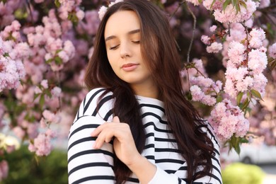 Beautiful woman near blossoming tree on spring day