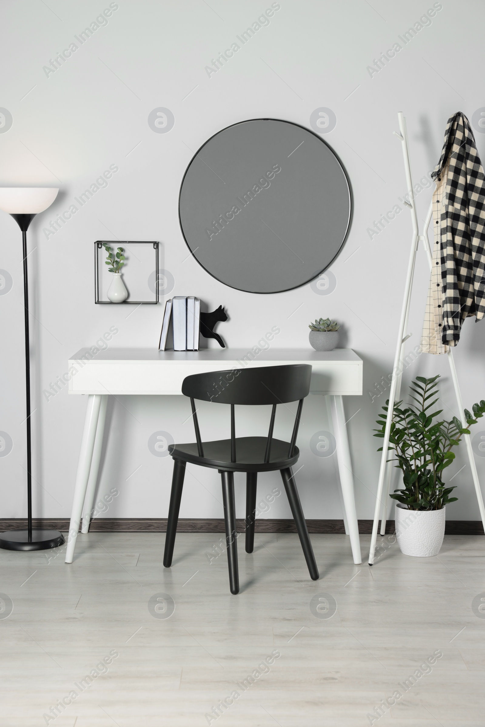 Photo of Stylish room interior with round mirror on white wall over desk