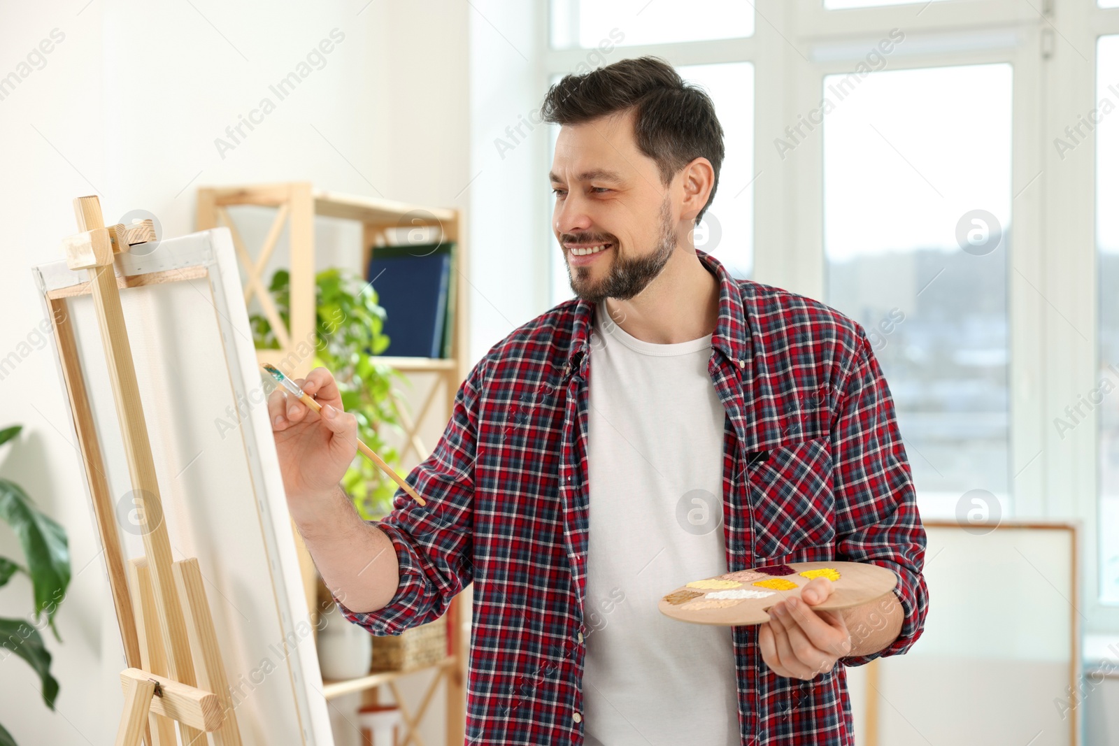 Photo of Handsome man painting in studio. Creative hobby