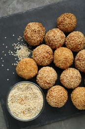 Delicious sesame balls and seeds on grey table, top view