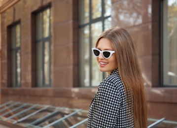 Photo of Young woman wearing stylish sunglasses on city street