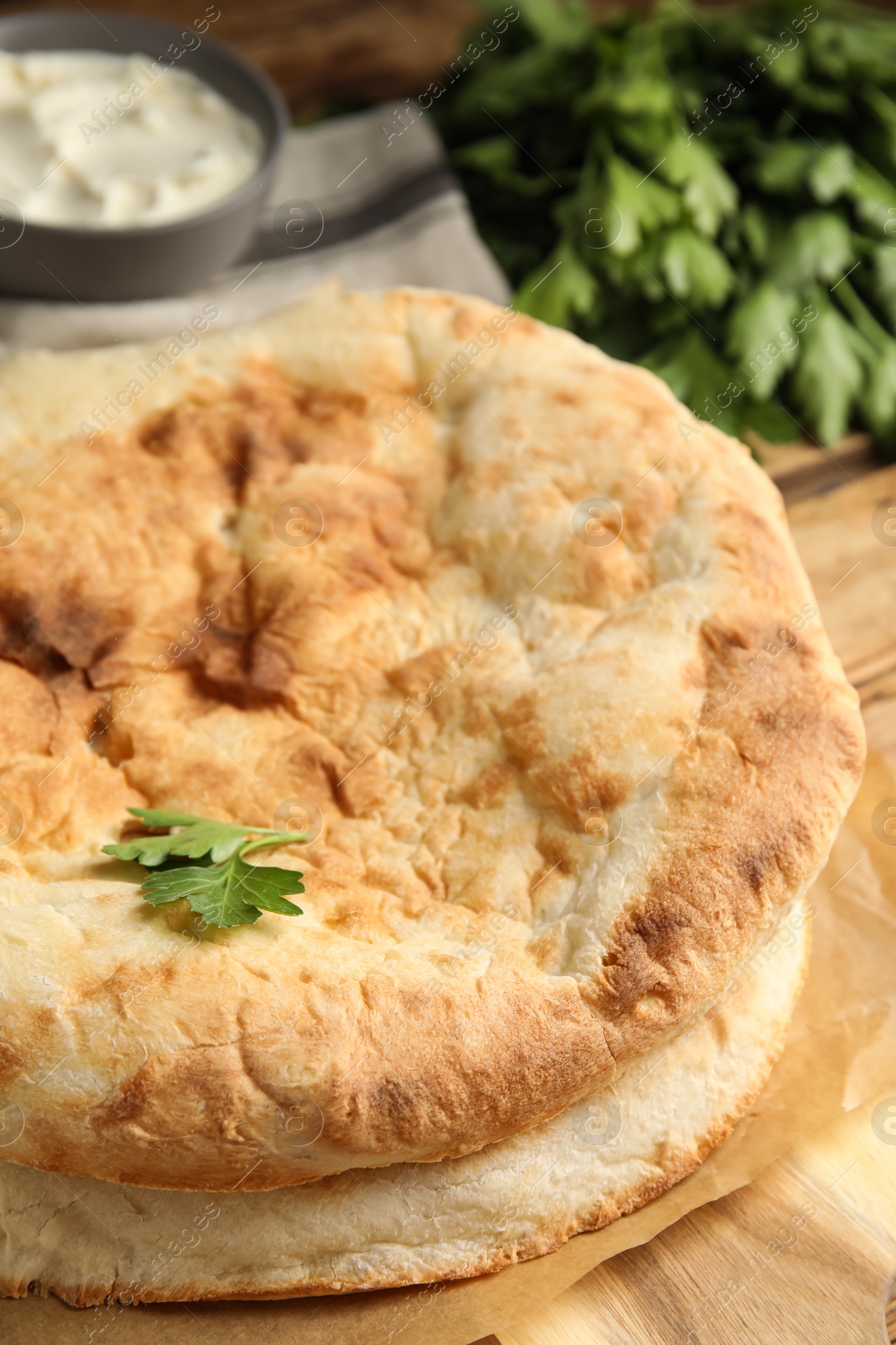 Photo of Loaves of delicious homemade pita bread on wooden table, closeup