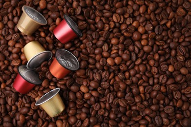 Many different coffee capsules on beans, top view. Space for text