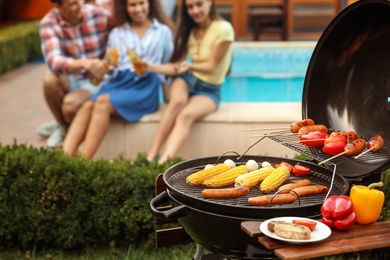 Photo of Barbecue grill with fresh food and blurred people on background