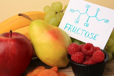 Card with word Fructose, delicious ripe fruits and raspberries on table, closeup