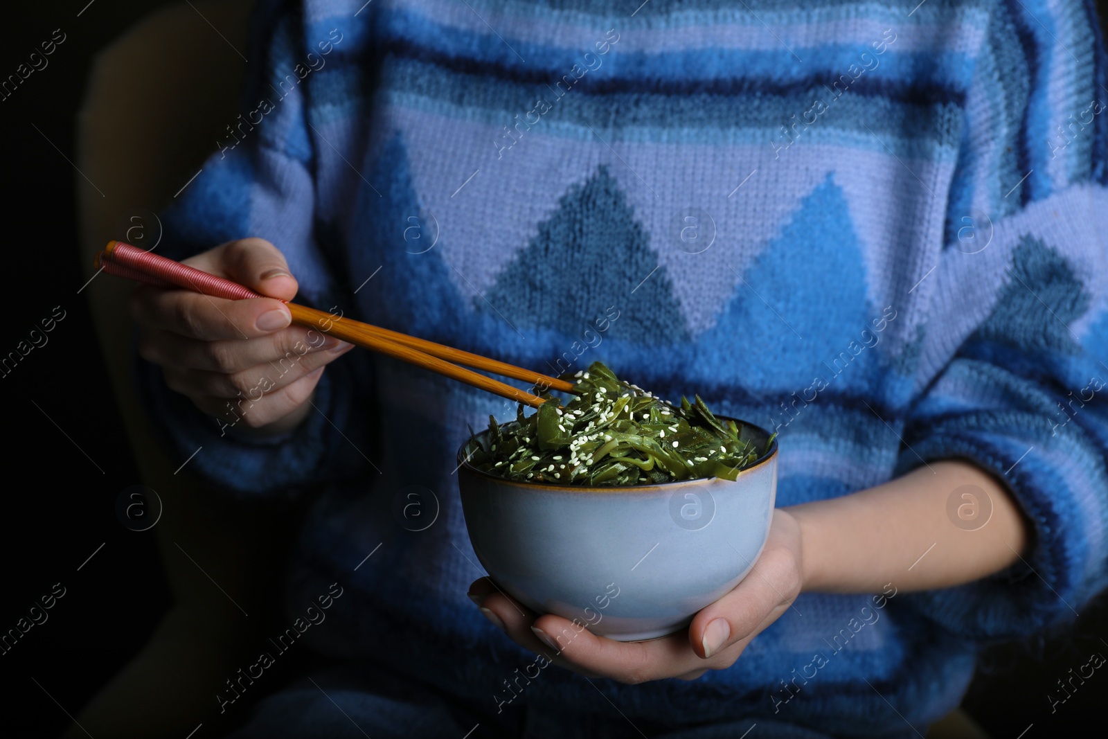 Photo of Woman eating fresh laminaria (kelp) seaweed, closeup