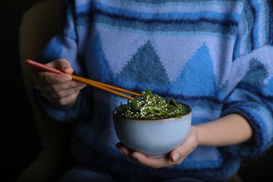 Photo of Woman eating fresh laminaria (kelp) seaweed, closeup