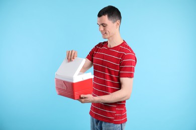 Man with cool box on light blue background