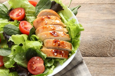 Delicious salad with chicken, cherry tomato and spinach on wooden table, closeup. Space for text