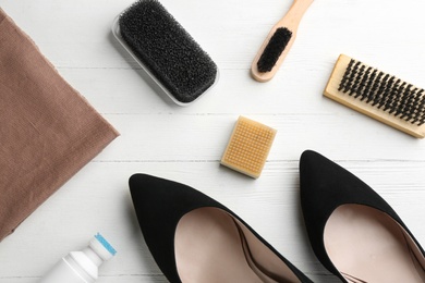 Photo of Stylish footwear with shoe care accessories on white wooden table, flat lay