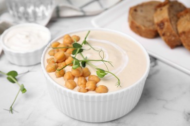 Tasty chickpea soup in bowl on white marble table, closeup