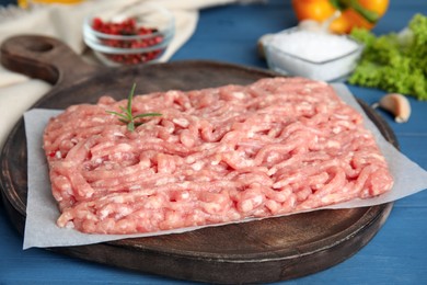 Raw chicken minced meat with rosemary on blue wooden table, closeup