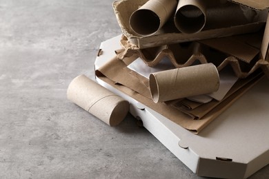 Stack of different waste paper on grey table, closeup. Space for text