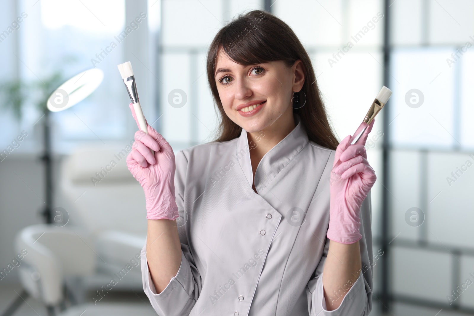 Photo of Cosmetologist with cosmetic brushes in modern clinic