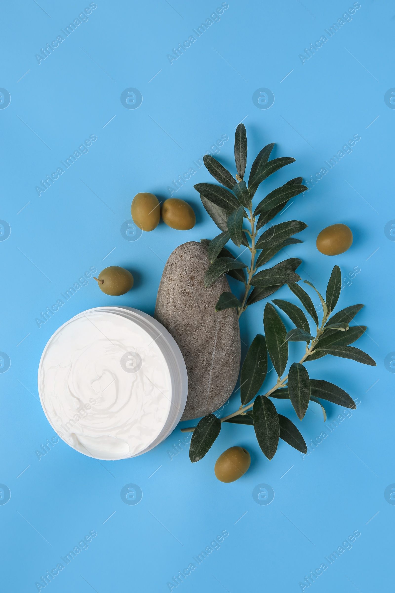 Photo of Flat lay composition with jar of cream and olives on light blue background
