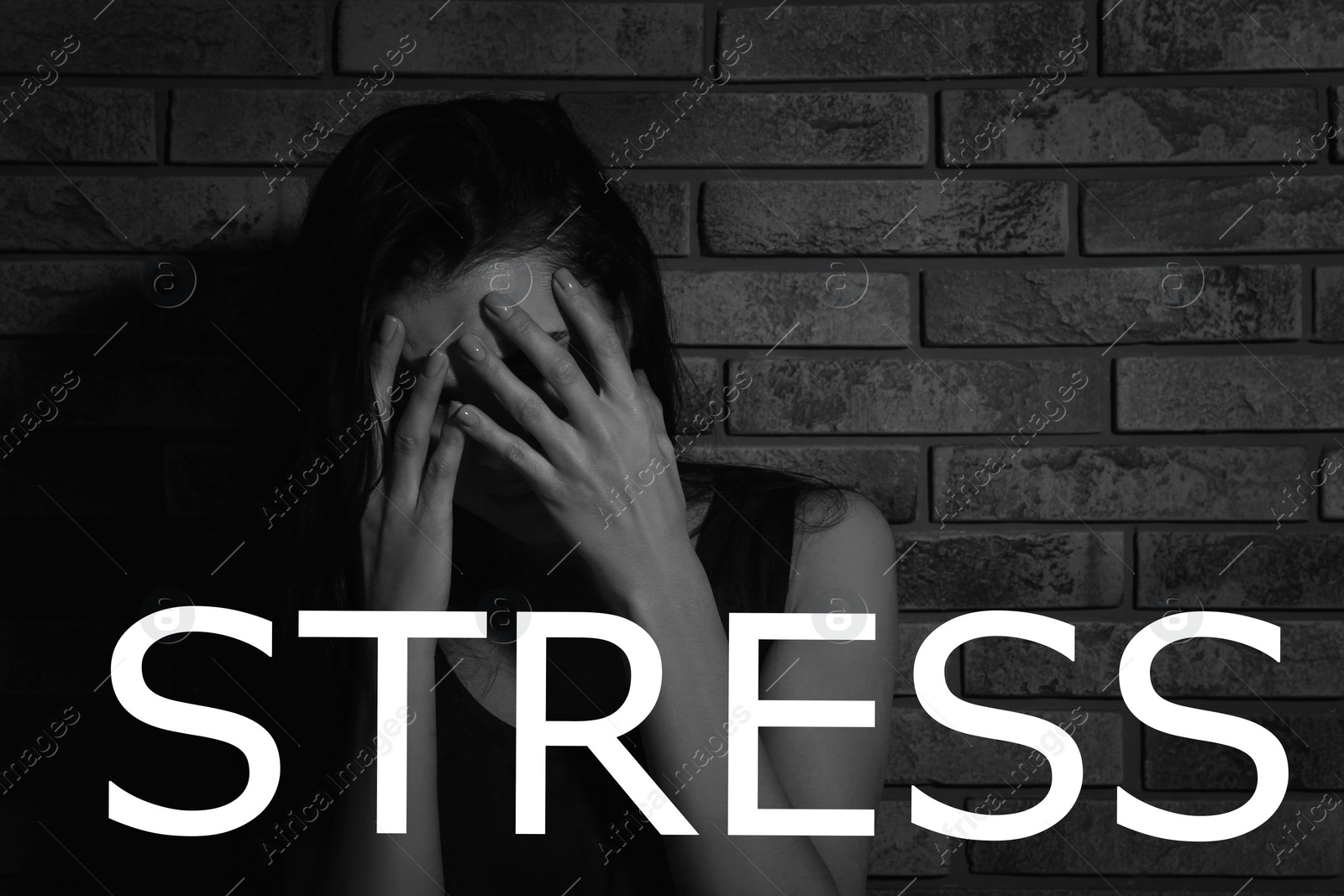 Image of Word STRESS and crying young woman near brick wall