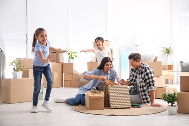 Happy family unpacking moving boxes at their new home