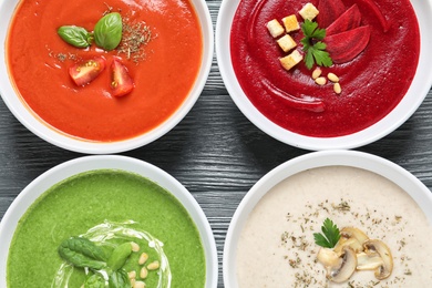 Various soups in bowls on wooden background, top view. Healthy food