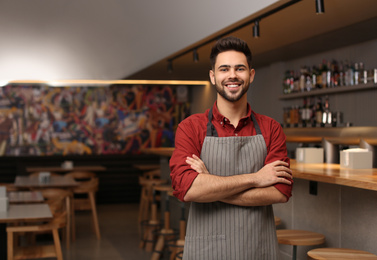 Photo of Young male business owner standing in his cafe. Space for text