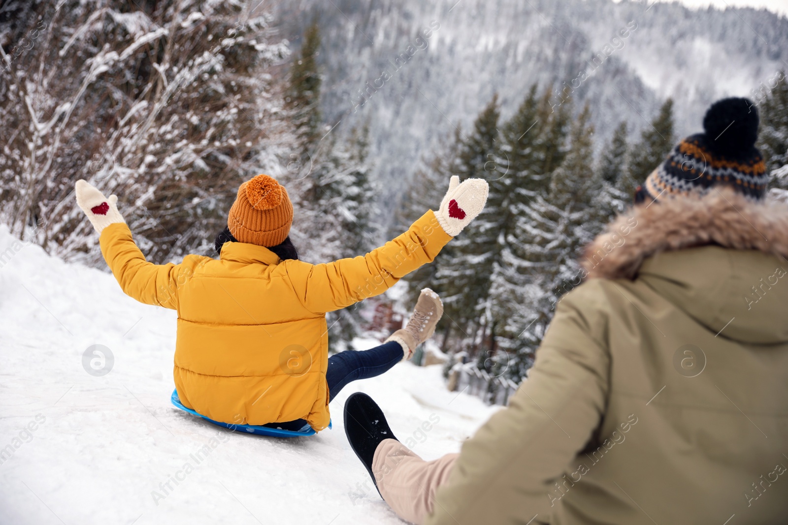 Photo of Couple having fun and sledding on snow. Winter vacation