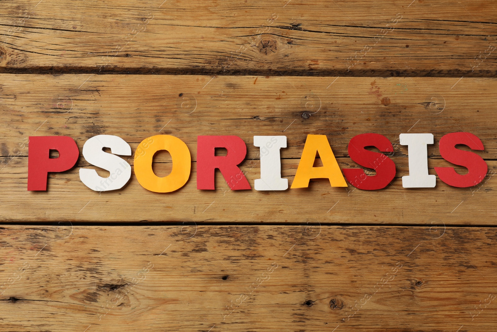 Photo of Word Psoriasis made of paper letters on wooden table, top view